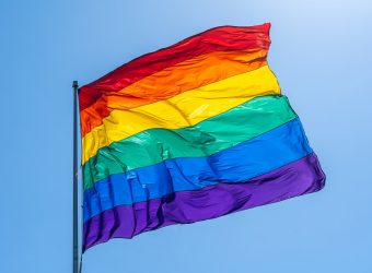 Rainbow gay pride flag on a blue sky