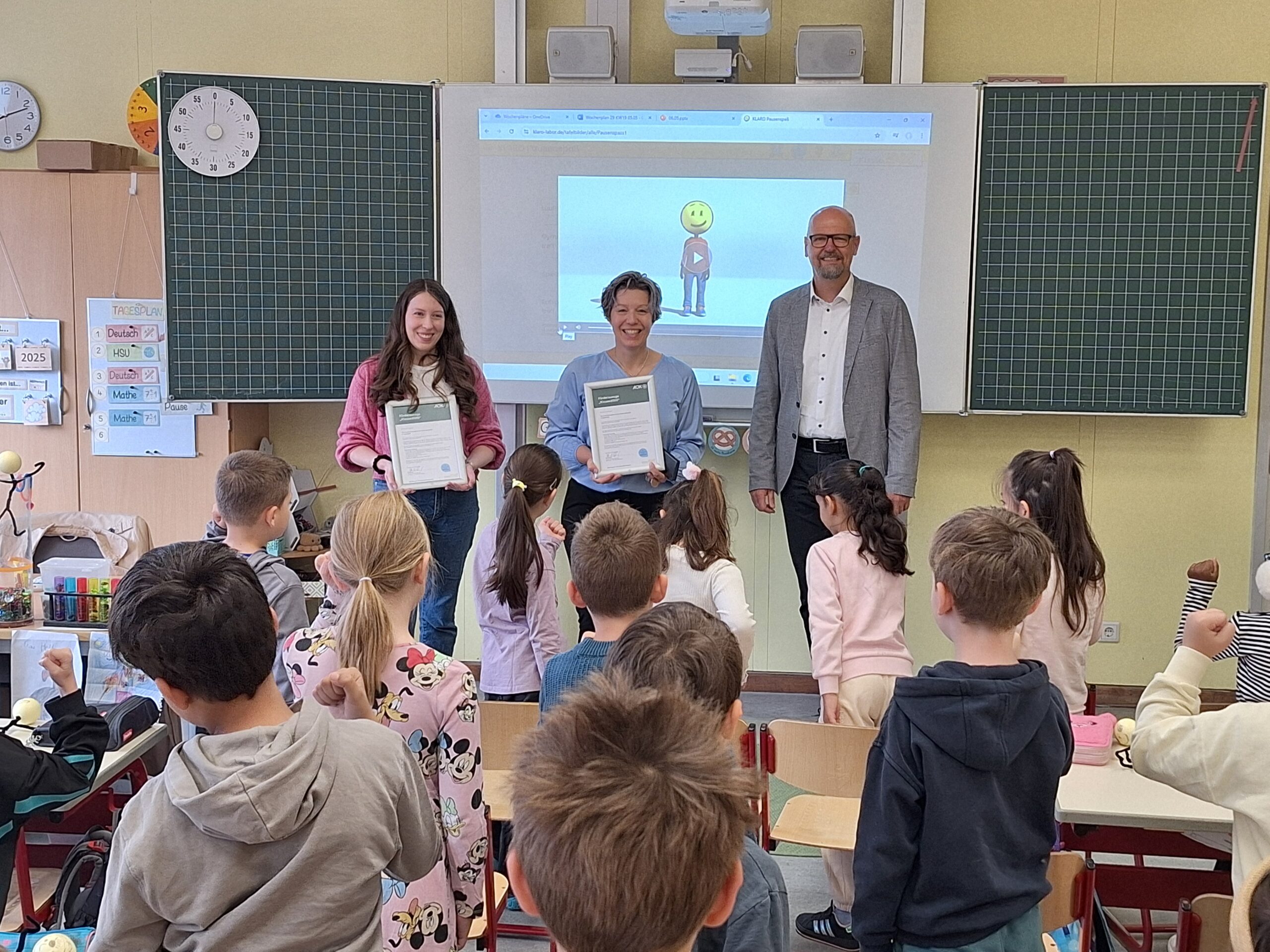 Die Schülerinnen und Schüler der Klassen 1a und 1b der Grundschule an der Pestaloz-zistraße in Ingolstadt führen eine Bewegungsübung aus dem Schulprogramm Klas-se2000 durch. v.l. Eva Heller (Klassenlehrerin), Iris Lechner (Konrektorin) und Ulrich Resch (Direktor AOK Ingolstadt) Urhebervermerk: © Rainer Stegmayr