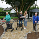 Foto: Im Caritas-Seniorenheim Ingolstadt-Gerolfing ist der Garten erneuert worden. Während Adelheid Neumaier (links) am Xylophon Harmony Glockenspiel und Edith Beringer (rechts) an der Babel Drum Spaß finden, zeigen sich Ursula Meyer und Einrichtungsleiterin Sarah Jacoby (Zweite von rechts) für die Unterstützung der GlücksSpirale dankbar. Foto: Caritas / Peter Esser