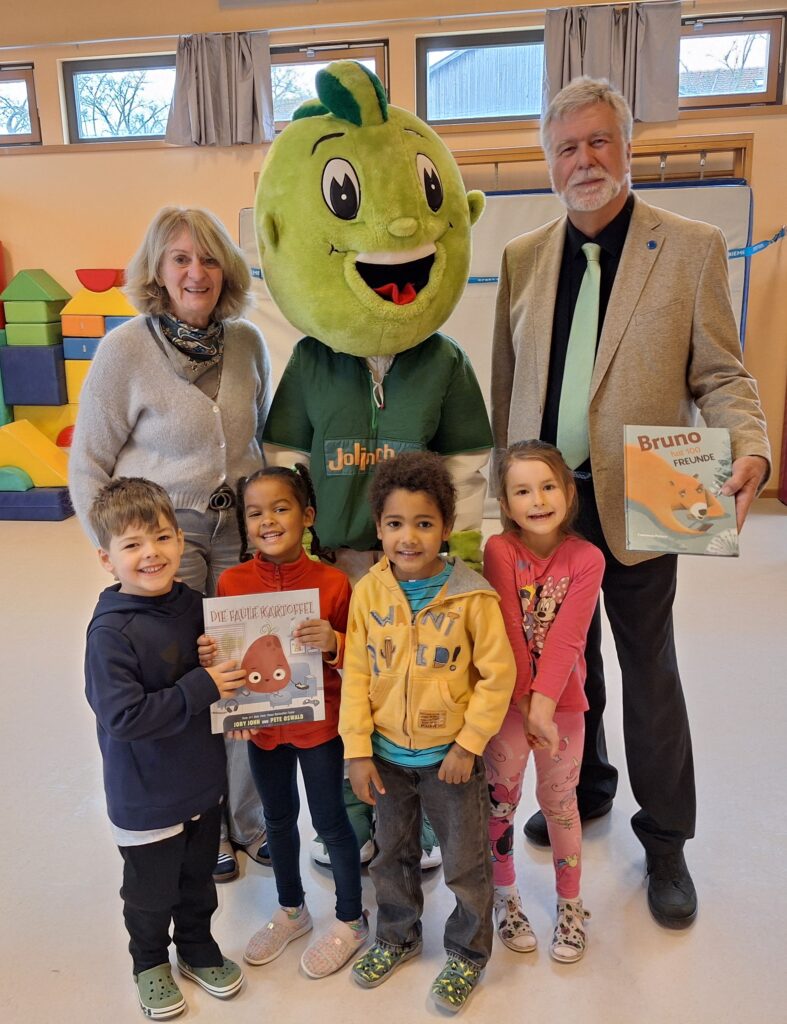 Bildunterschrift: v.l.h. Kindergartenleiterin Beate Braunstorfer, das AOK-Maskottchen Jolinchen und Ewald Kommer zusammen mit einigen Kindern beim Vorlesetag im städt. Kindergarten Bunte Welt in Geisenfeld Urhebervermerk: Rainer Stegmayr