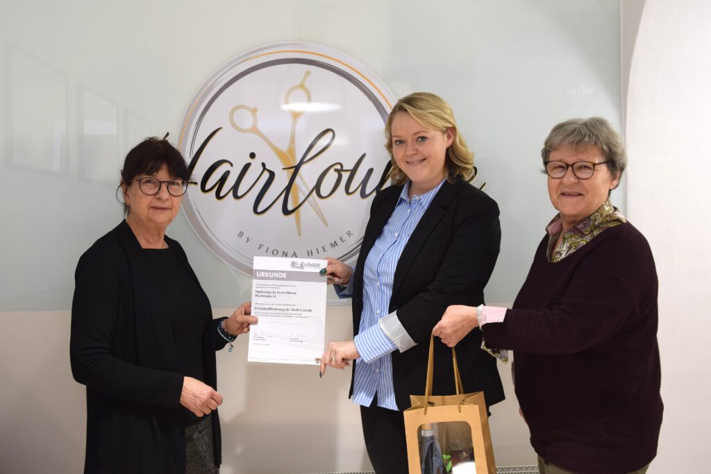 Die „Hairlounge“ führt Friseurmeisterin Fiona Hiemer (Mitte) seit August in der Eichstätter Pfahlstraße. In der Gründungsphase unterstützt die Stadt Eichstätt sie mit einem Mietzuschuss. Die offizielle Urkunde dazu gab es aus den Händen von Bürgermeisterin Elisabeth Gabler (links) und der Standortbeauftragten Beate Michel. Foto: Sophie Fries/Stadt Eichstätt