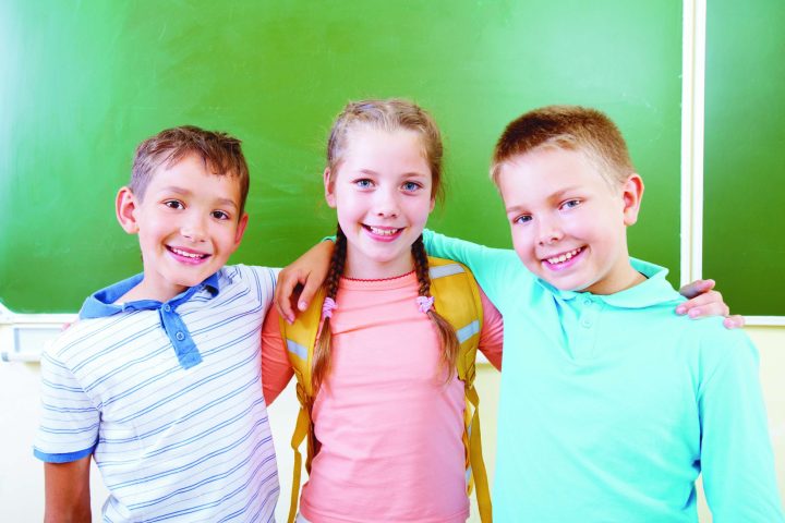Portrait of lovely girl and two schoolboys looking at camera