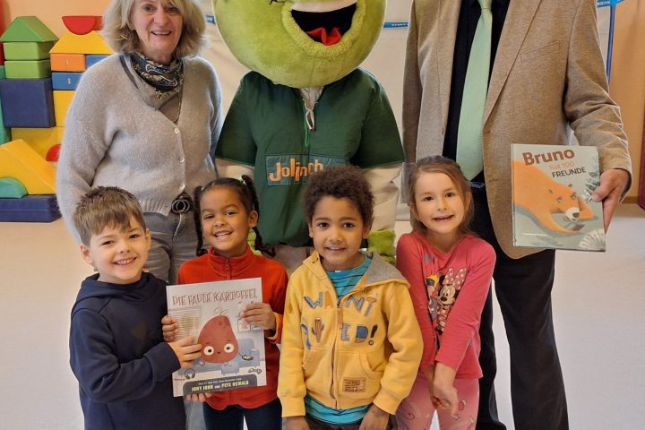 Bildunterschrift: v.l.h. Kindergartenleiterin Beate Braunstorfer, das AOK-Maskottchen Jolinchen und Ewald Kommer zusammen mit einigen Kindern beim Vorlesetag im städt. Kindergarten Bunte Welt in Geisenfeld Urhebervermerk: Rainer Stegmayr