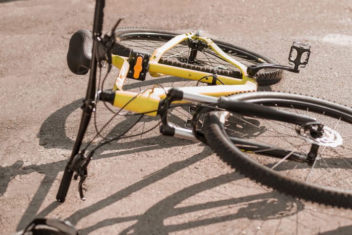 Traffic collision. Accident on the road with black car and sports bicycle lying with helmet on sunny day