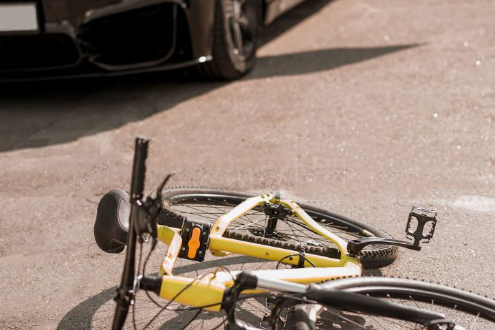 Traffic collision. Accident on the road with black car and sports bicycle lying with helmet on sunny day