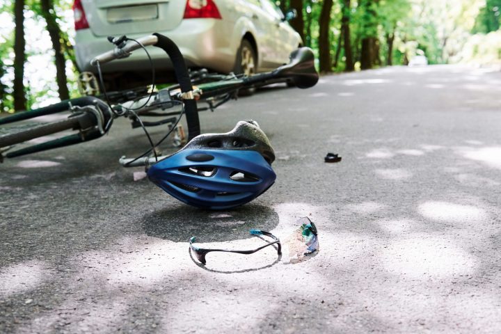 Conception of carelessness. Bicycle and silver colored car accident on the road at forest at daytime.