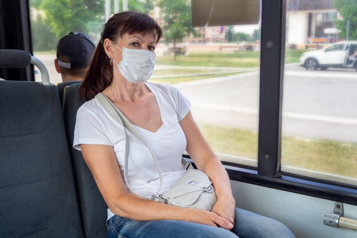 Adult woman in a protective mask rides alone in an empty on public transport in the city. Social distance. Bus passengers are protected from the coronavirus. New normal. lifestyle during the pandemic.