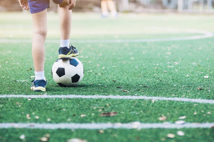 Boy standing with ball in football field ready to start or play new game - sport player concept