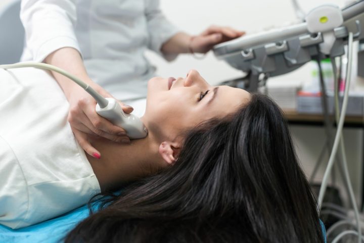 Ultrasound scanning diagnostic of woman thyroid gland in clinic, doctor runs ultrasound sensor
