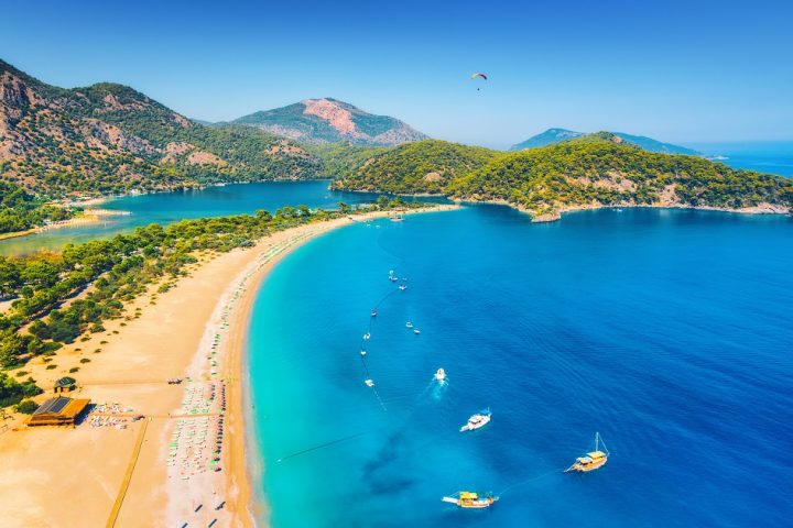 Amazing aerial view of Blue Lagoon in Oludeniz, Turkey. Summer landscape with sea spit, boats and yachts, green trees, azure water, sandy beach in sunny day. Travel. Top view of national park. Nature