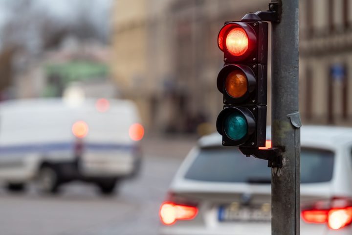 blurred view of city traffic with traffic lights, in the foreground a semaphore with a red light