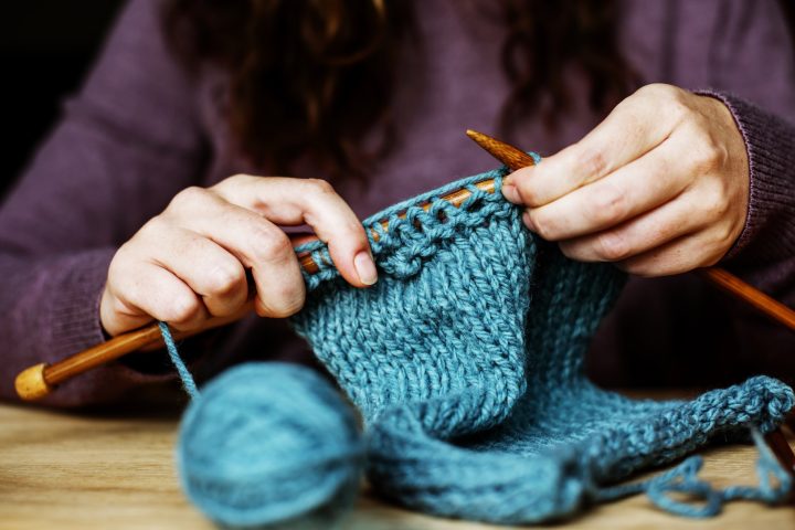 Closeup of hands knitting on wooden table