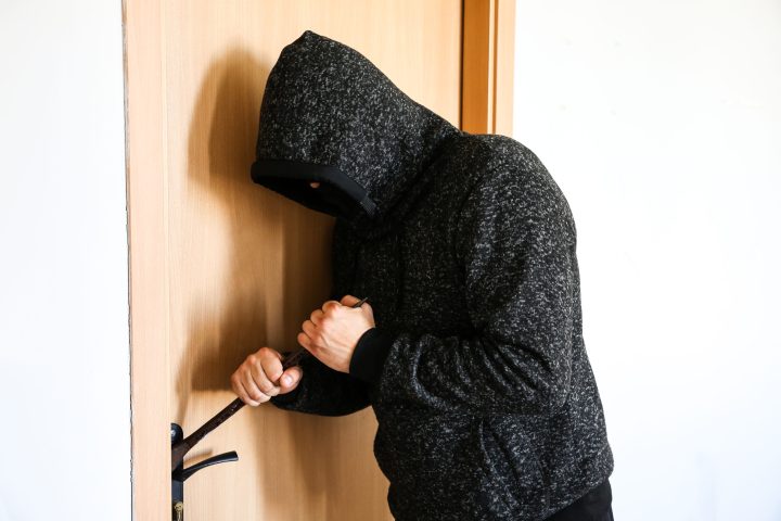 Einbruch Criminal with crowbar near the doors. Robber breaking into house