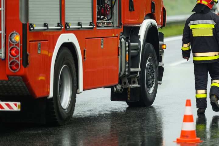 Highway Traffic Accident Site Firefighter Securing Traffic. Firetruck and Ambulance.