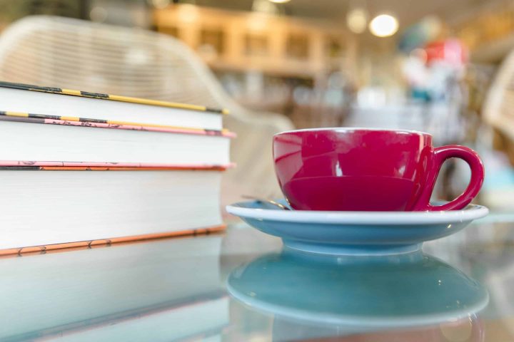 red-coffee-cup-near-books-reflective-desk_freepiks-scaled