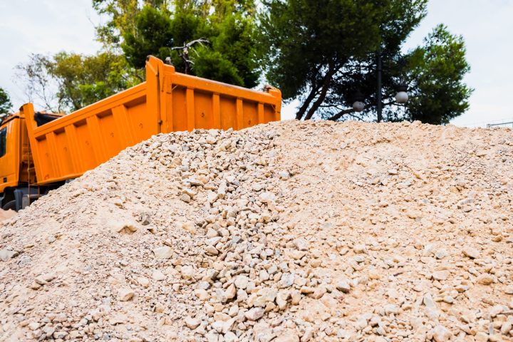 Truck out of focus in the background delivers several tons of sand and gravel for construction work.